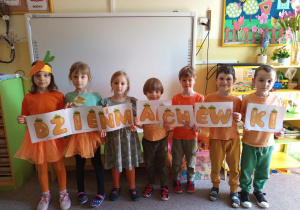 Grupka dzieci prezentuje napis "dzień marchewki"