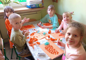 Grupka dzieci wykonuje prace plastyczne przy stolikach