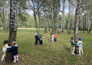 Przedszkolaki przytulają się do drzew