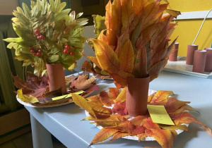 Praca plastyczno - techniczna z talerzyków i rolek po papierze toaletowym, ozdobiona świeżymi liśćmi