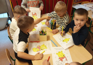 Grupa chłopców koloruje malowankę misia