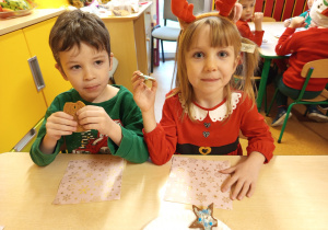 Nikita i Melania siedzą przy stole i jedzą pierniczki