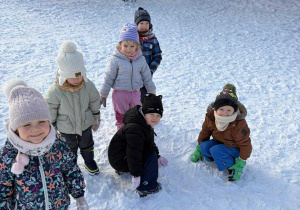 Wiktoria, Kacper, Otylia, Maks, Emilka i Michał próbują ulepić bałwana, ale śnieg niestety jest zbyt sypki.