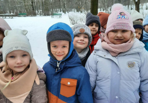 7 dzieci uśmiecha się do zdjęcia stojąc na polanie