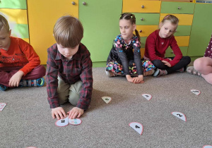 chłopiec układa dwie połówki serca siedząc na dywanie