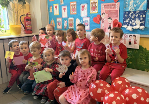 Dzieci z grupy I siedzą w holu przedszkola, a Pani wręcza im walentynki z poczty walentynkowej