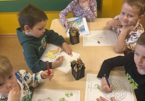 Kacper, Kinga, Janek i Oliwier wykonują karty pracy z dinozaurami