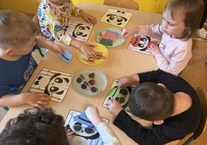 Kinga, Kajetan, Artem ubierają pandy w stroje odpowiadające kolorom bambusów