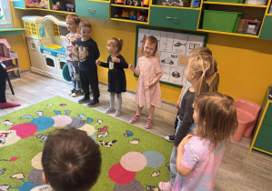 Dzieci w kole naśladują gesty i śpiewają piosenkę